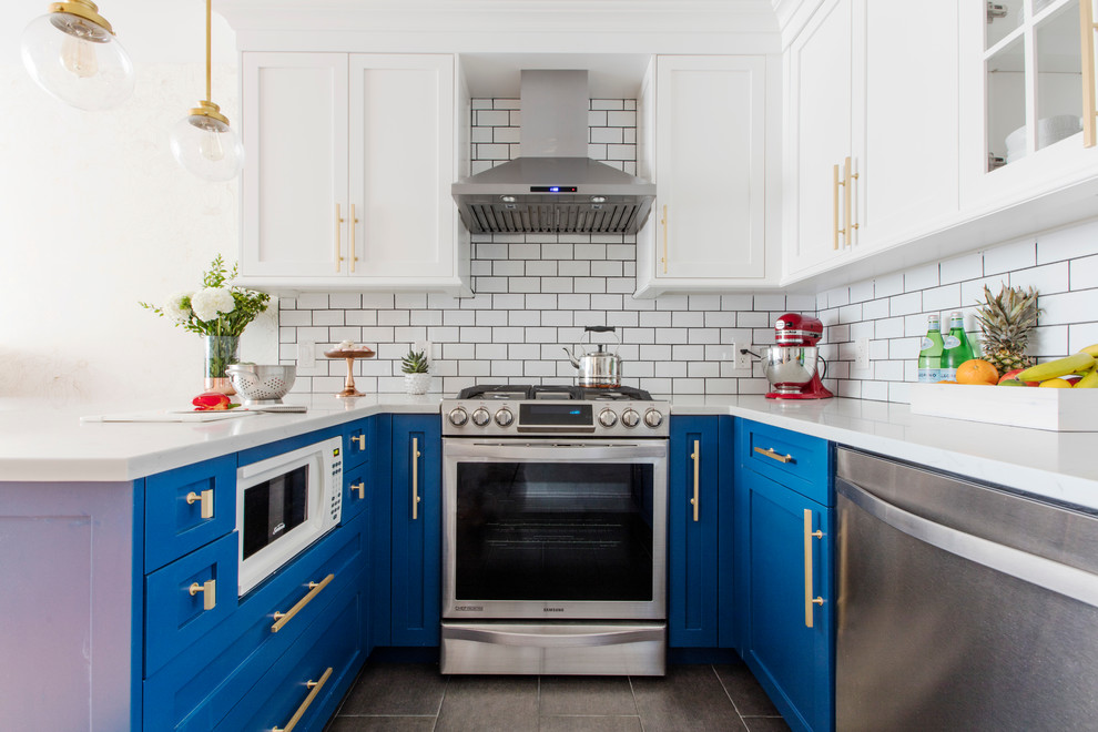 Design ideas for a small transitional u-shaped eat-in kitchen in New York with recessed-panel cabinets, blue cabinets, white splashback, subway tile splashback, stainless steel appliances, a peninsula, a farmhouse sink and grey floor.