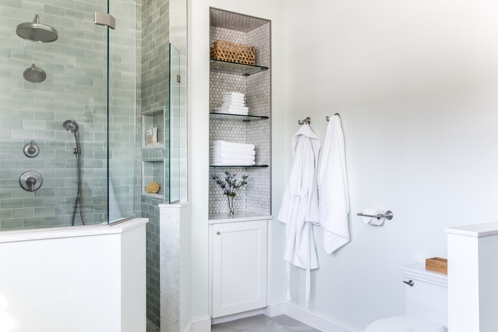 This is an example of a transitional master bathroom in Boston with recessed-panel cabinets, white cabinets, a freestanding tub, a curbless shower, a one-piece toilet, green tile, ceramic tile, marble floors, an undermount sink, marble benchtops, grey floor, an open shower and grey benchtops.