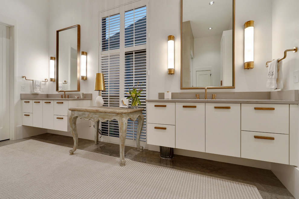 This is an example of a large contemporary master bathroom in New Orleans with flat-panel cabinets, white cabinets, a freestanding tub, an alcove shower, white walls, concrete floors, an undermount sink, grey floor, a hinged shower door and beige benchtops.