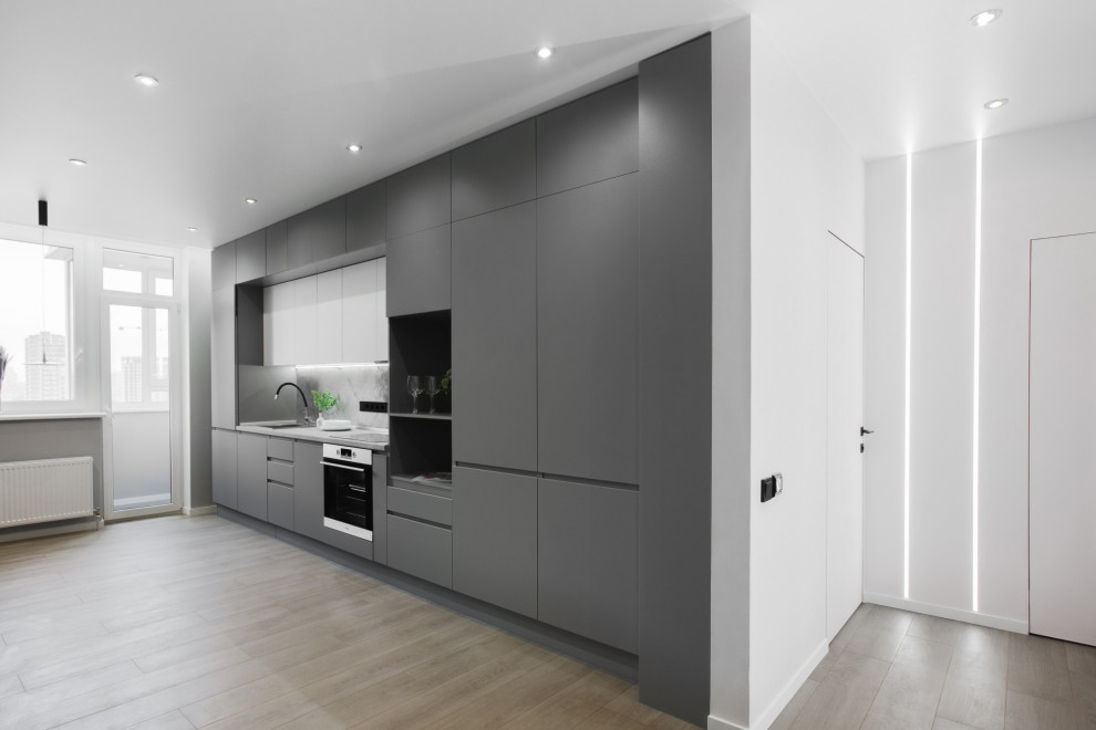 Mid-sized contemporary single-wall open plan kitchen in Other with a drop-in sink, flat-panel cabinets, grey cabinets, grey splashback, stainless steel appliances, laminate floors, no island, beige floor and grey benchtop.