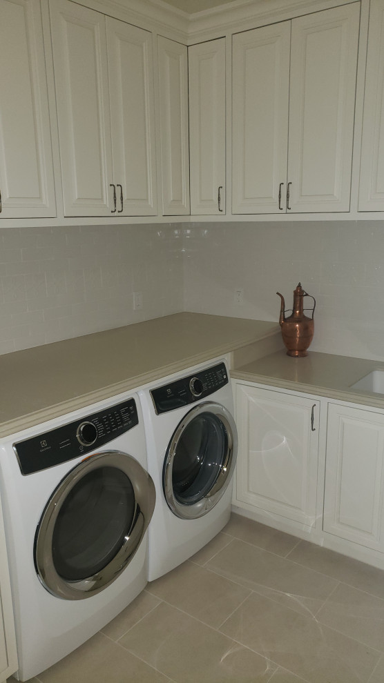 This is an example of a medium sized classic l-shaped separated utility room in Orange County with a submerged sink, raised-panel cabinets, distressed cabinets, engineered stone countertops, an integrated washer and dryer and beige worktops.