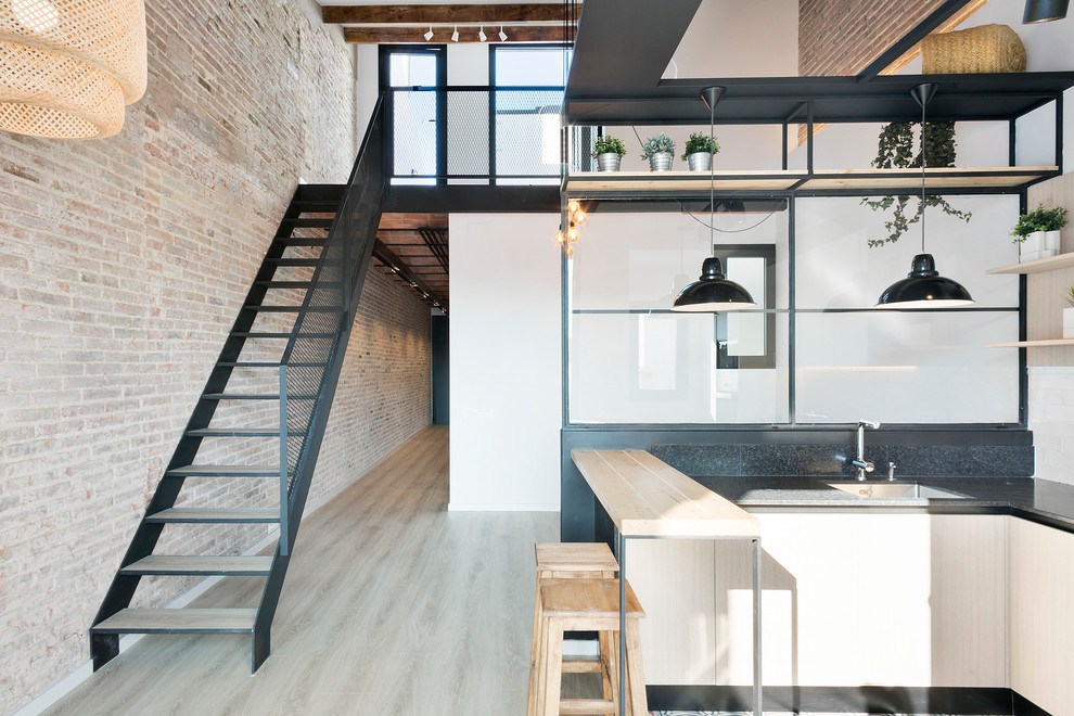 Inspiration for a small industrial u-shaped eat-in kitchen in Barcelona with light hardwood floors, flat-panel cabinets, white cabinets, white splashback, subway tile splashback, stainless steel appliances and a peninsula.