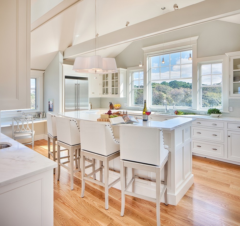 Traditional kitchen in Boston with shaker cabinets, white cabinets, stainless steel appliances, medium hardwood floors, with island and brown floor.