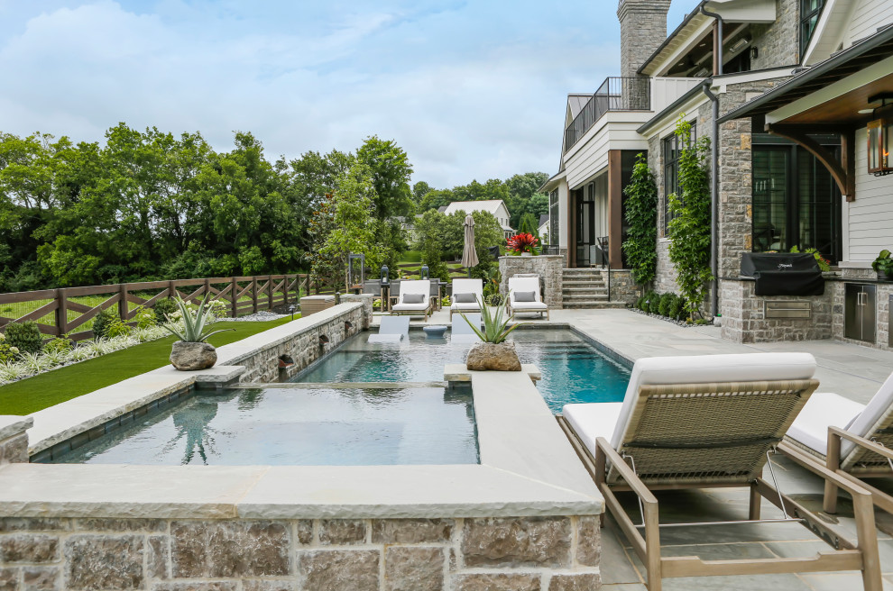 Diseño de piscina de estilo de casa de campo de tamaño medio rectangular en patio trasero con privacidad y adoquines de piedra natural