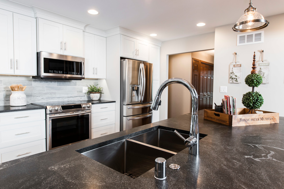 Inspiration for a transitional single-wall eat-in kitchen in Milwaukee with an undermount sink, shaker cabinets, white cabinets, soapstone benchtops, grey splashback, stone tile splashback, stainless steel appliances, dark hardwood floors and with island.