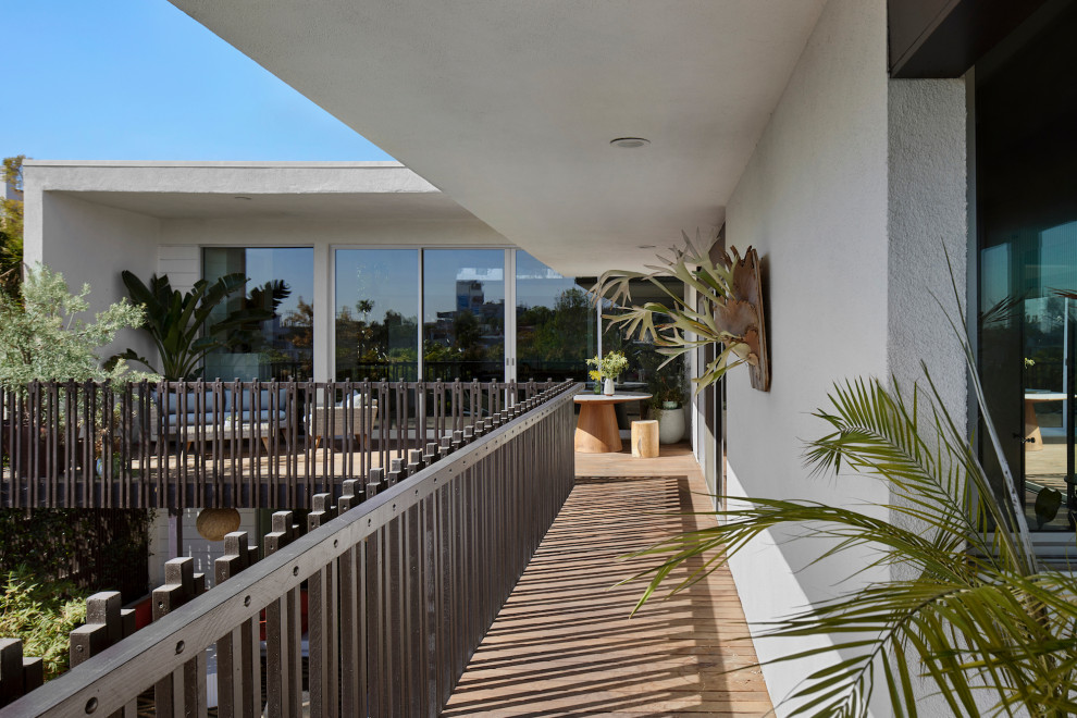 Exemple d'un grand balcon rétro avec des solutions pour vis-à-vis, une extension de toiture et un garde-corps en bois.
