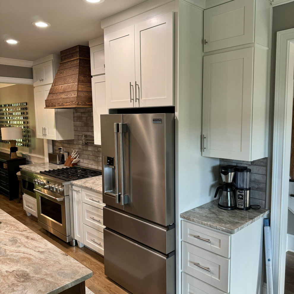 Transitional galley medium tone wood floor and brown floor eat-in kitchen photo in Atlanta with an undermount sink, shaker cabinets, white cabinets, granite countertops, gray backsplash, ceramic backsplash, stainless steel appliances, an island and multicolored countertops