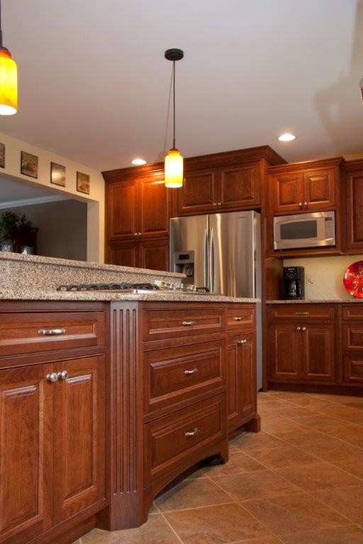 This is an example of a large country l-shaped eat-in kitchen in Philadelphia with medium wood cabinets, with island, an undermount sink, beaded inset cabinets, white splashback and stainless steel appliances.
