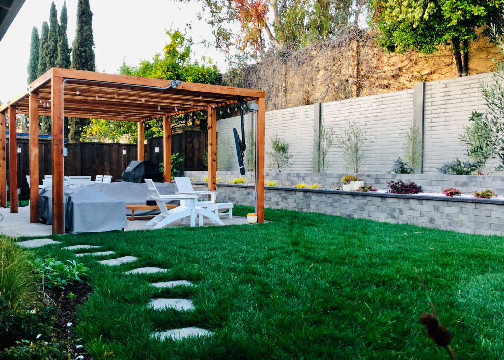 Photo of a mid-sized contemporary full sun backyard brick and stone fence landscaping in San Francisco with a pergola.