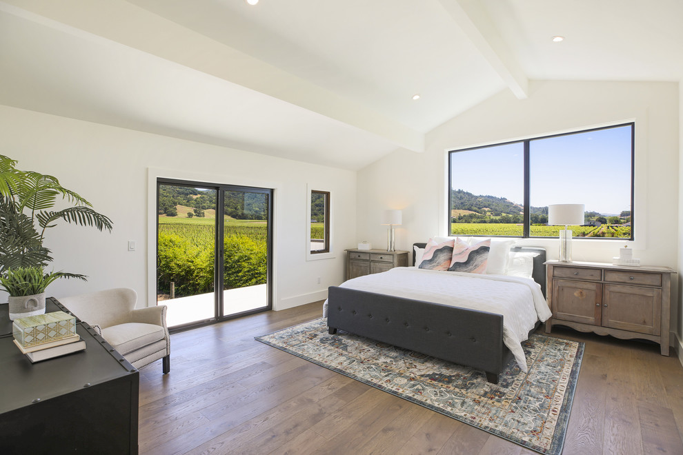 This is an example of a country bedroom in San Francisco with white walls, dark hardwood floors and brown floor.