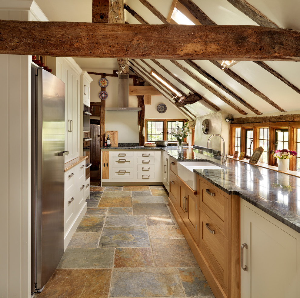 This is an example of a mid-sized country u-shaped kitchen in London with a farmhouse sink, shaker cabinets, white cabinets and stainless steel appliances.