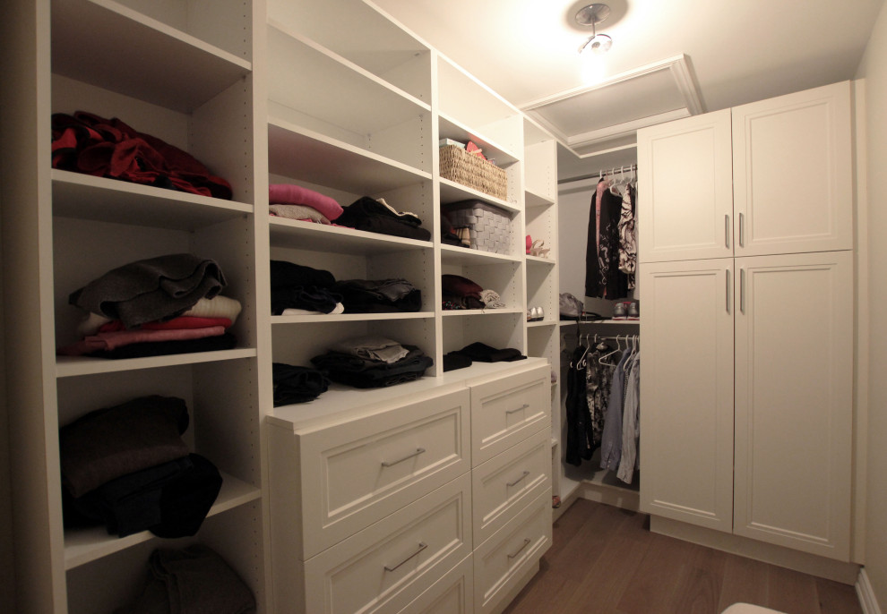 Design ideas for a large transitional women's walk-in wardrobe in Toronto with flat-panel cabinets, white cabinets, light hardwood floors and brown floor.