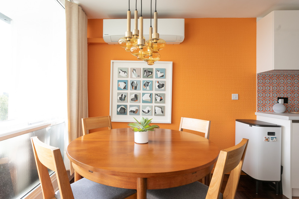 50 tals inredning av en liten matplats, med orange väggar, vinylgolv och en hängande öppen spis