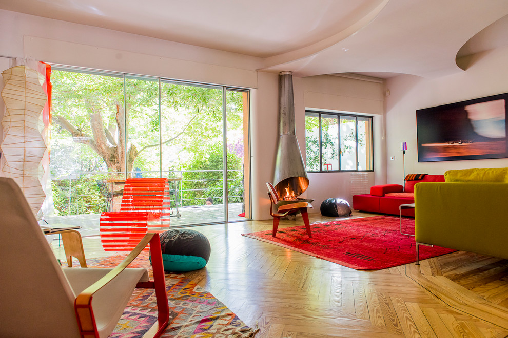 Photo of a large contemporary enclosed family room in Madrid with medium hardwood floors, white walls, a standard fireplace and no tv.