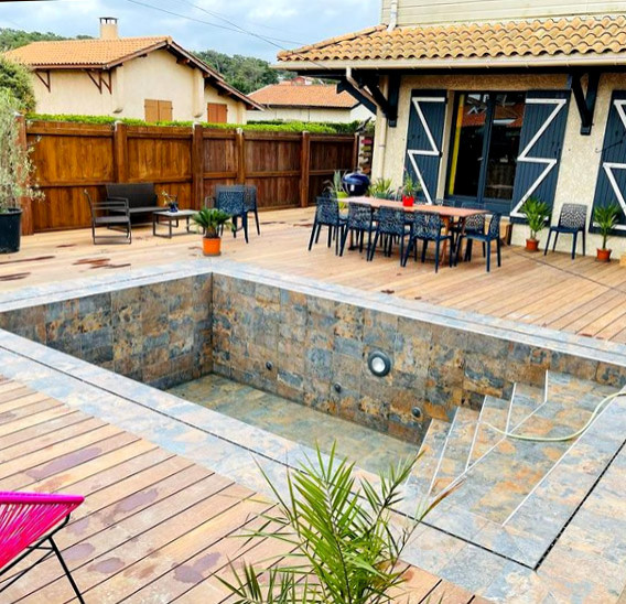 Idée de décoration pour une piscine à débordement marine de taille moyenne et rectangle avec une terrasse en bois.