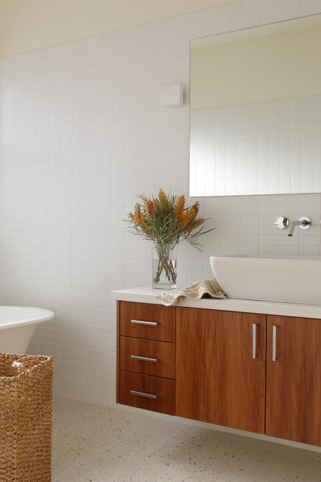 This is an example of a mid-sized contemporary master bathroom in Brisbane with a vessel sink, medium wood cabinets, engineered quartz benchtops, a freestanding tub, white tile, porcelain tile, white walls and flat-panel cabinets.
