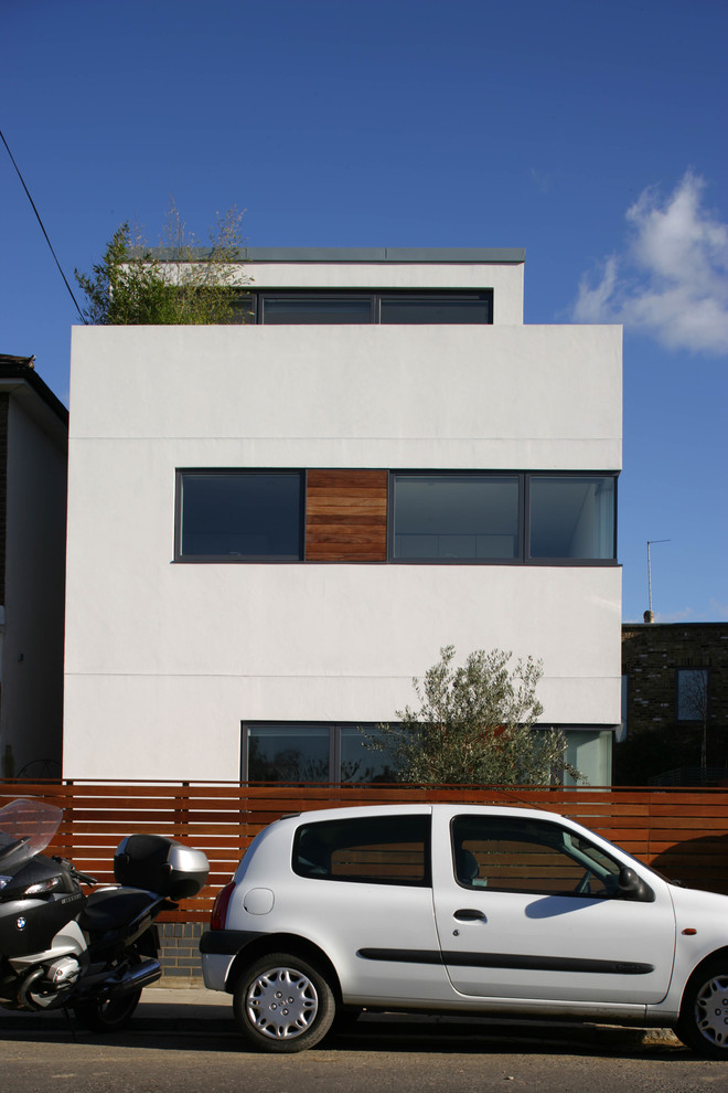 Photo of a small contemporary three-storey stucco white exterior in London.