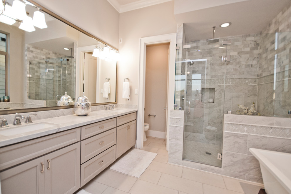 This is an example of a large transitional master bathroom in San Francisco with flat-panel cabinets, beige cabinets, a drop-in tub, an open shower, a one-piece toilet, white tile, beige walls, porcelain floors, a drop-in sink, marble benchtops, beige floor, a hinged shower door and white benchtops.