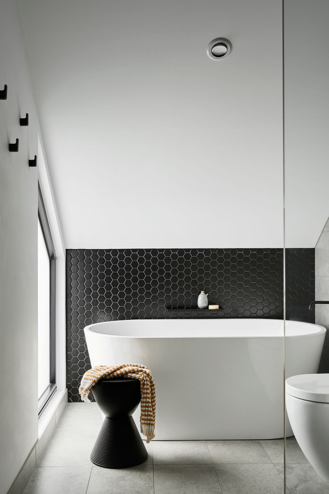 Design ideas for a small contemporary master bathroom in Geelong with light wood cabinets, a freestanding tub, a corner shower, a wall-mount toilet, gray tile, porcelain tile, grey walls, porcelain floors, engineered quartz benchtops, grey floor, a hinged shower door, white benchtops, a single vanity, a floating vanity, vaulted and an integrated sink.