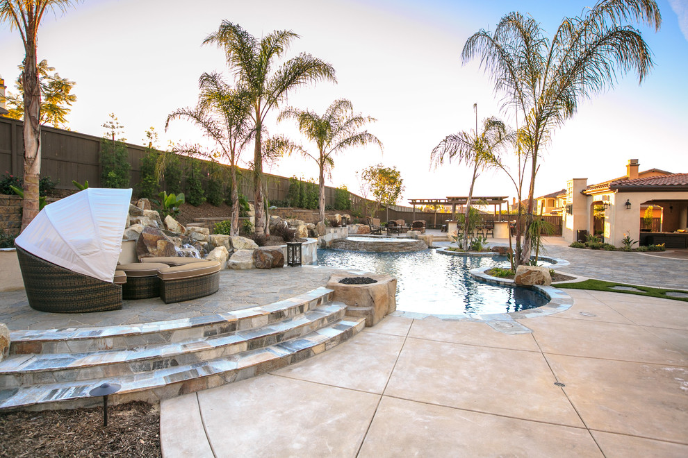 Photo of a large mediterranean backyard custom-shaped natural pool in San Diego with a water feature and concrete pavers.