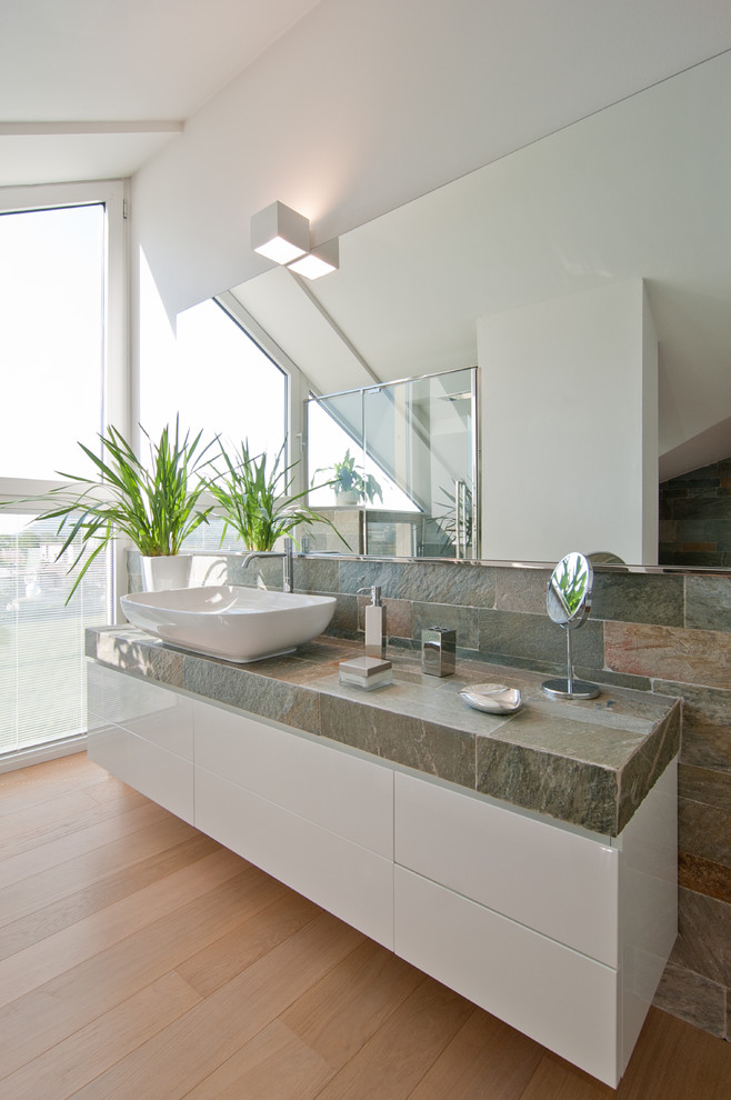 Contemporary bathroom in Venice with flat-panel cabinets, white cabinets, white walls, medium hardwood floors, a vessel sink, tile benchtops, brown floor and grey benchtops.