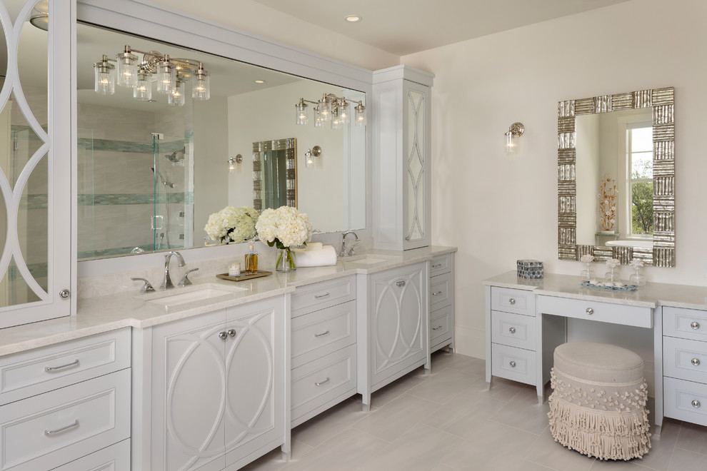 Photo of a mid-sized tropical master bathroom in Miami with furniture-like cabinets, white cabinets, a corner shower, white tile, white walls, porcelain floors, an undermount sink, engineered quartz benchtops, grey floor, a hinged shower door and white benchtops.