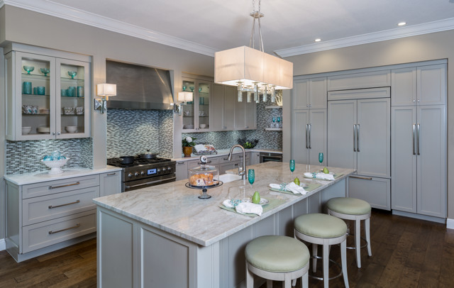 タンパの中サイズのトランジショナルスタイルのおしゃれなキッチン (エプロンフロントシンク、シェーカースタイル扉のキャビネット、グレーのキャビネット、珪岩カウンター、青いキッチンパネル、ガラスタイルのキッチンパネル、パネルと同色の調理設備、濃色無垢フローリング) の写真