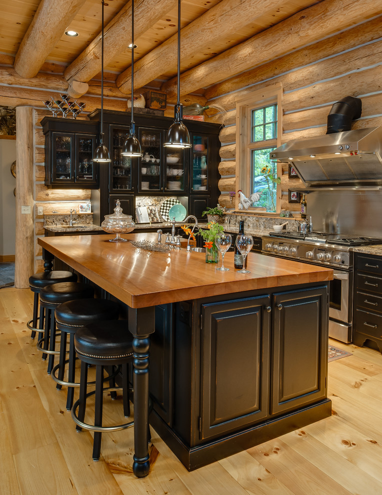 Mountain style l-shaped eat-in kitchen photo with an undermount sink, raised-panel cabinets, black cabinets, wood countertops, multicolored backsplash, stone slab backsplash and stainless steel appliances