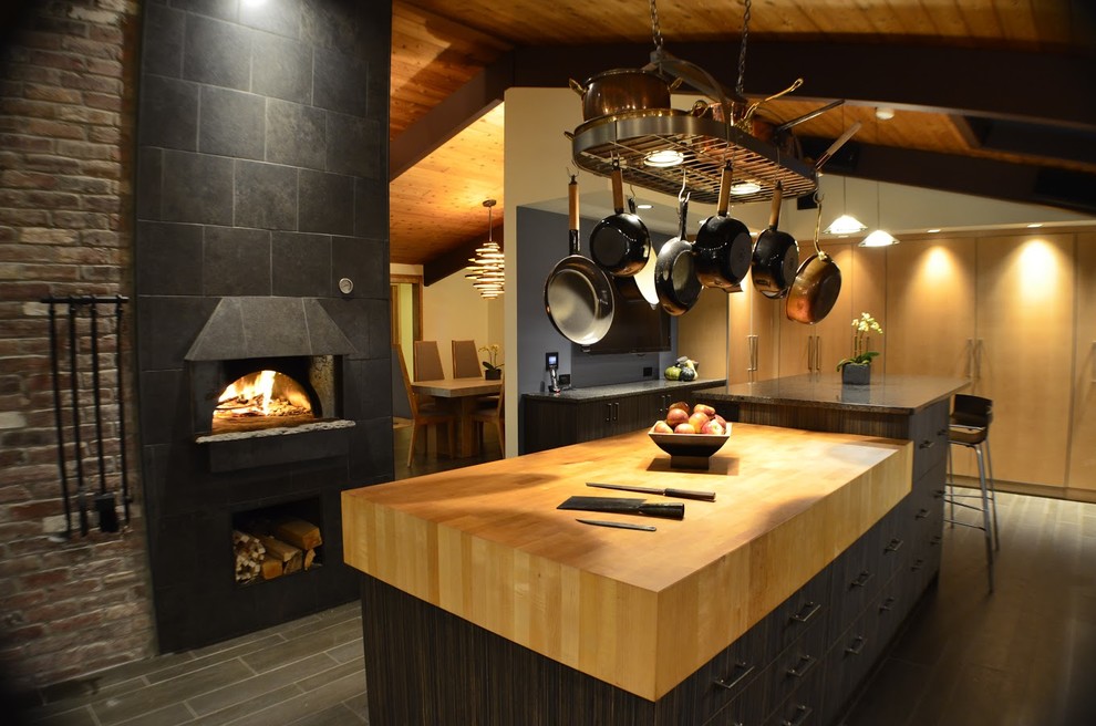 Large country kitchen in Boston with porcelain floors, black floor, flat-panel cabinets, dark wood cabinets, wood benchtops, brick splashback and multiple islands.