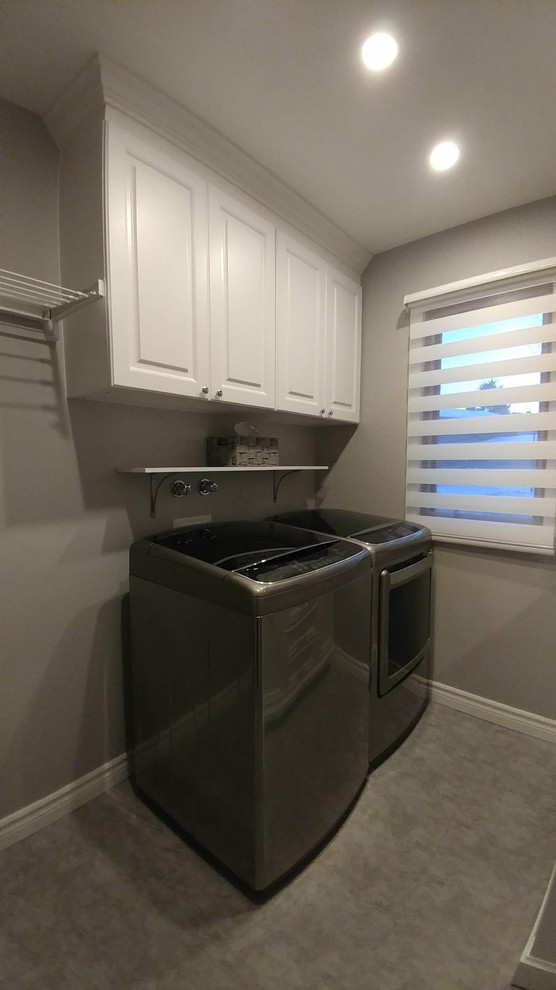 This is an example of a small transitional galley utility room in Montreal with a single-bowl sink, raised-panel cabinets, white cabinets, quartzite benchtops, grey walls, vinyl floors, a side-by-side washer and dryer, grey floor and grey benchtop.