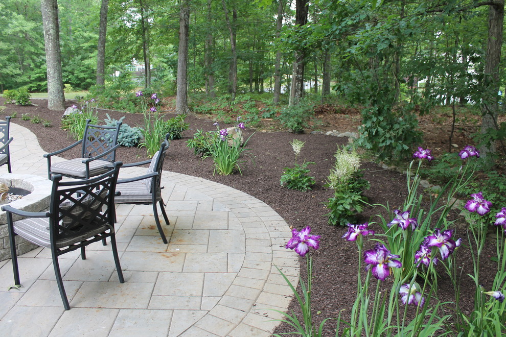 This is an example of a mid-sized traditional backyard patio in New York with a fire feature, natural stone pavers and no cover.