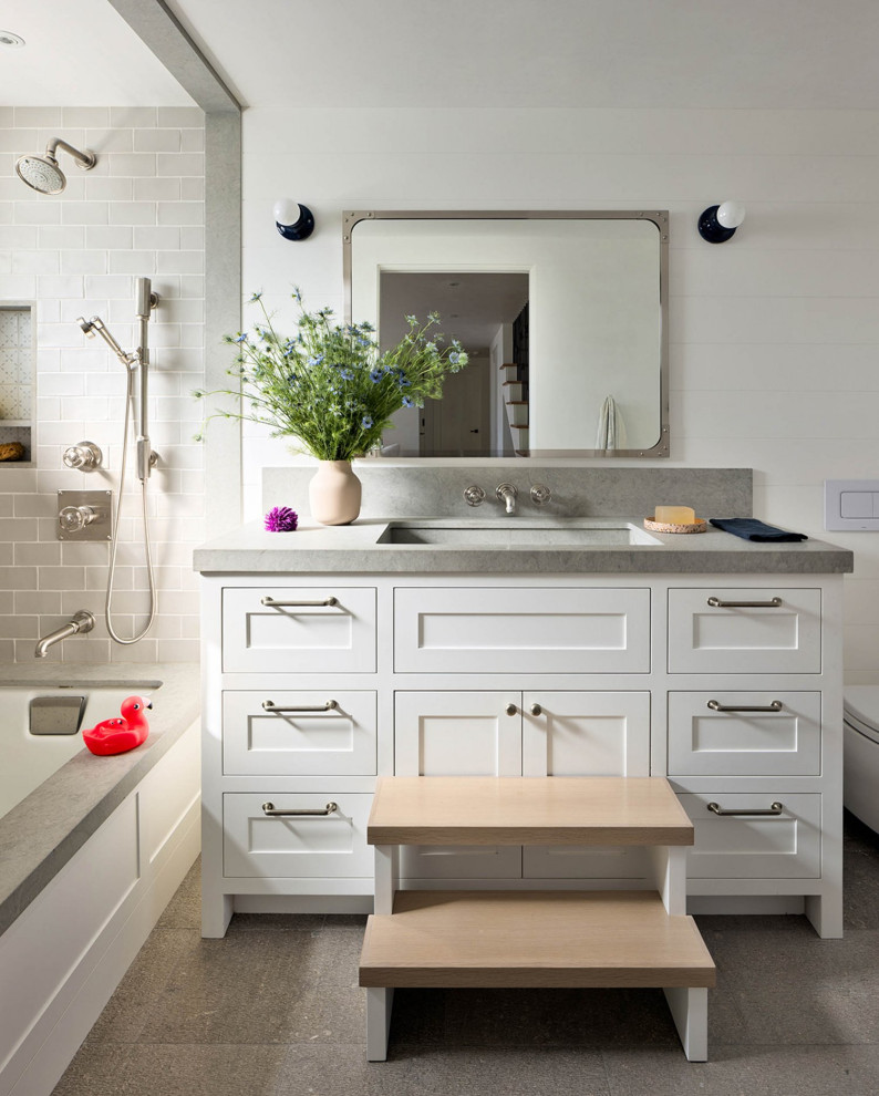 Foto på ett mellanstort vintage grå badrum för barn, med skåp i shakerstil, vita skåp, vita väggar, ett platsbyggt badkar, en dusch/badkar-kombination, en bidé, vit kakel, ett integrerad handfat, bänkskiva i kalksten och grått golv