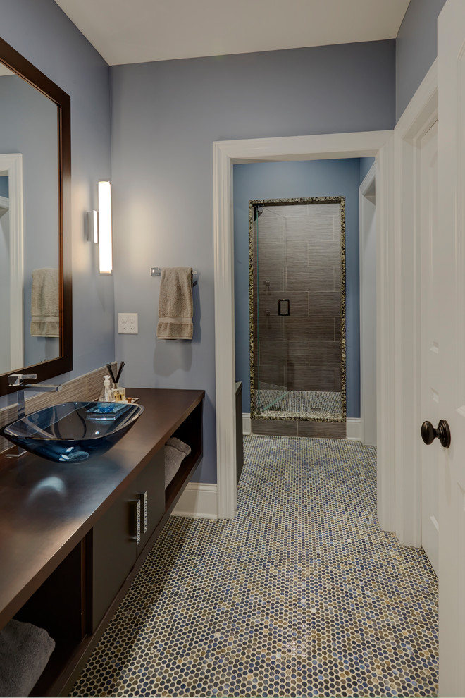 This is an example of a large modern bathroom in Chicago with flat-panel cabinets, dark wood cabinets, an alcove shower, a two-piece toilet, gray tile, porcelain tile, blue walls, mosaic tile floors, a vessel sink, wood benchtops, multi-coloured floor, a hinged shower door, brown benchtops, a single vanity and a floating vanity.