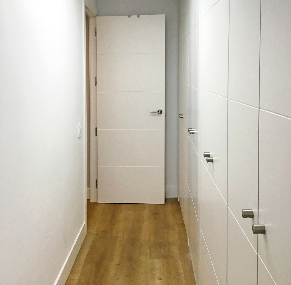 This is an example of a large classic walk-in wardrobe for women in Madrid with white cabinets, laminate floors and beige floors.