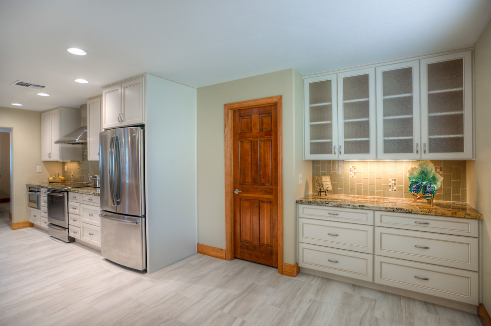 Inspiration for a large transitional galley porcelain tile eat-in kitchen remodel in Phoenix with an undermount sink, shaker cabinets, white cabinets, granite countertops, green backsplash, glass tile backsplash, stainless steel appliances and an island
