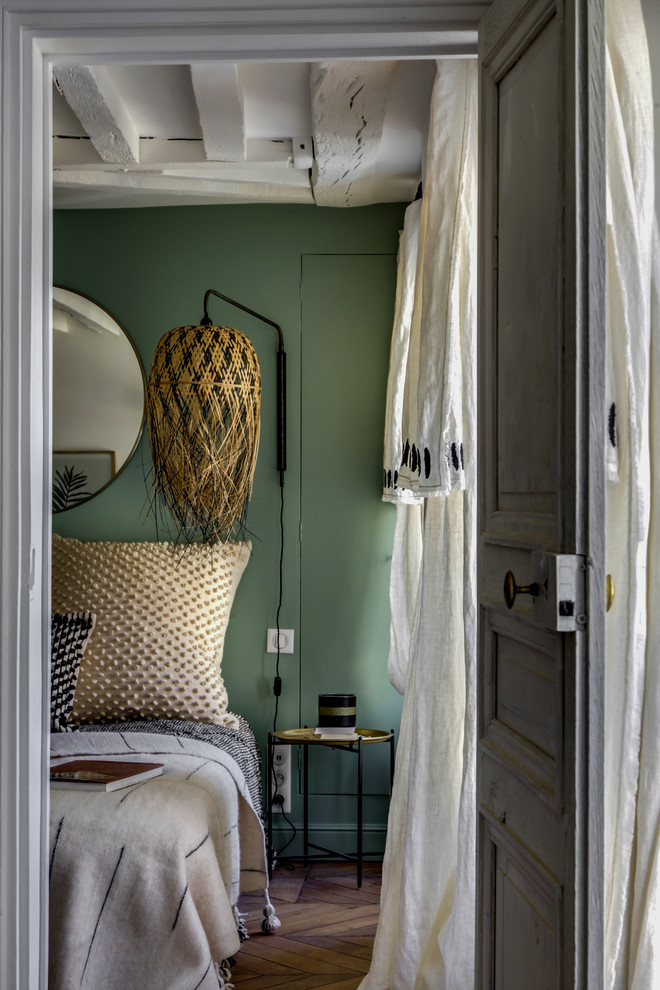 Photo of a small eclectic master bedroom in Paris with green walls, medium hardwood floors, no fireplace and brown floor.