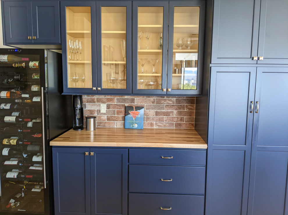 Cette image montre un bar de salon design avec un placard à porte shaker, des portes de placard bleues et un plan de travail en bois.