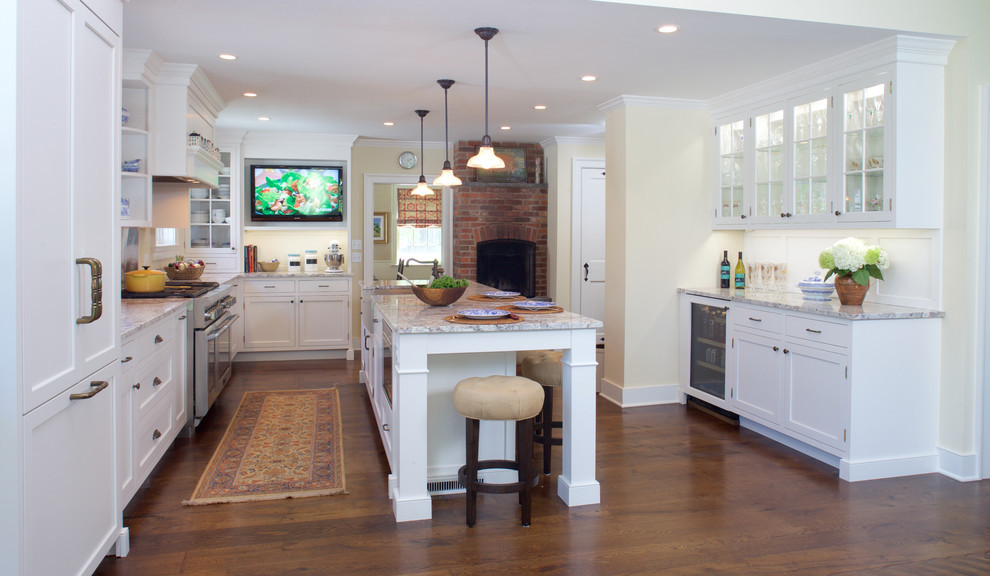 This is an example of a mid-sized traditional u-shaped eat-in kitchen in New York with a farmhouse sink, recessed-panel cabinets, white cabinets, granite benchtops, yellow splashback, dark hardwood floors, with island and panelled appliances.