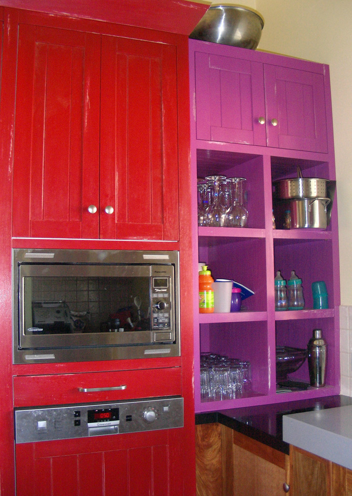 Large eclectic u-shaped kitchen pantry in Melbourne with an undermount sink, shaker cabinets, red cabinets, quartz benchtops, multi-coloured splashback, glass sheet splashback, stainless steel appliances, vinyl floors and multiple islands.