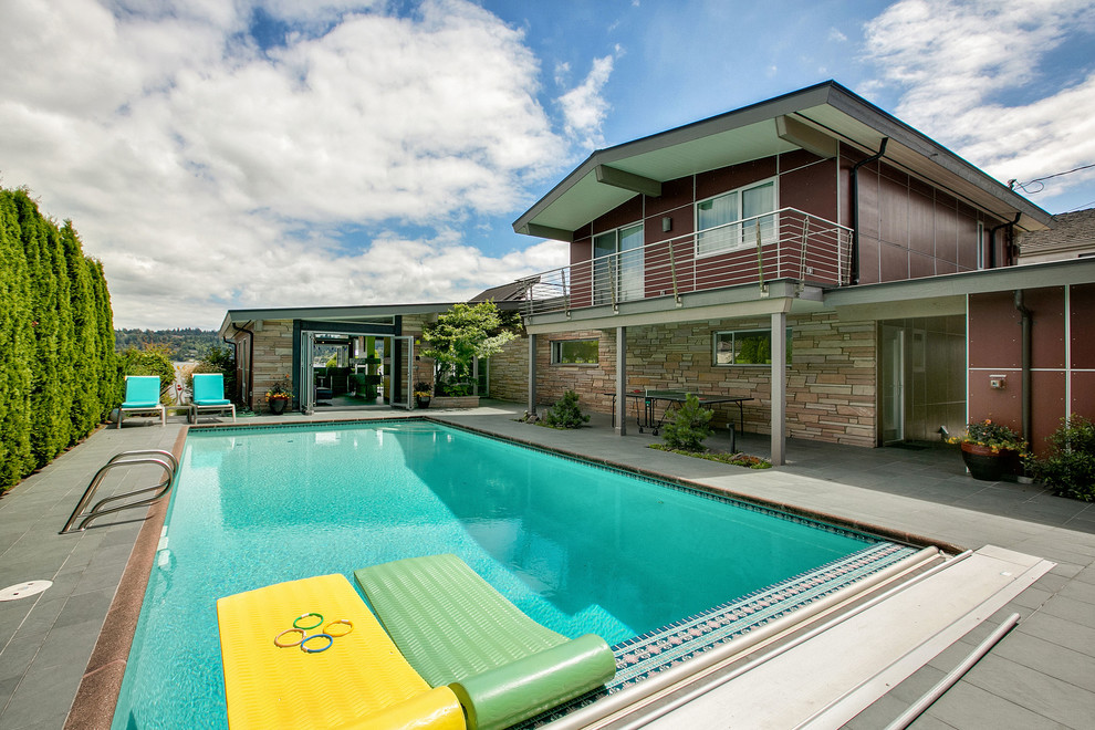 This is an example of a mid-sized midcentury backyard rectangular pool in Seattle with concrete pavers.