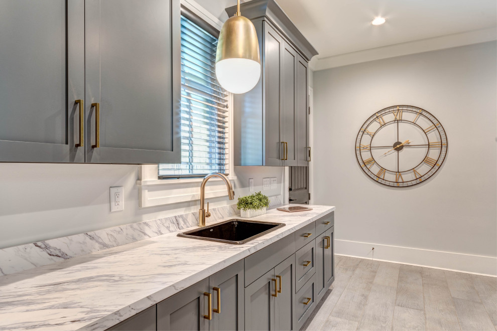 Inspiration for an expansive arts and crafts galley utility room in Atlanta with a drop-in sink, shaker cabinets, grey cabinets, laminate benchtops, grey walls, porcelain floors, a side-by-side washer and dryer, grey floor and white benchtop.
