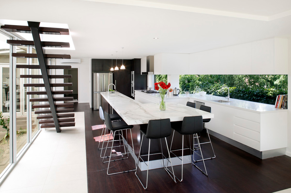 Photo of a large modern single-wall eat-in kitchen in Sydney with flat-panel cabinets, marble benchtops, stainless steel appliances, white cabinets, dark hardwood floors, with island, a single-bowl sink and glass sheet splashback.