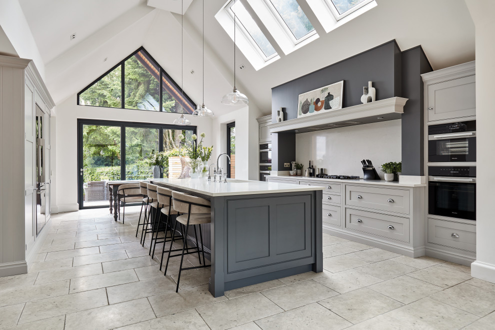 Large traditional galley open plan kitchen in Manchester with a built-in sink, shaker cabinets, grey cabinets, quartz worktops, white splashback, engineered quartz splashback, stainless steel appliances, an island and white worktops.