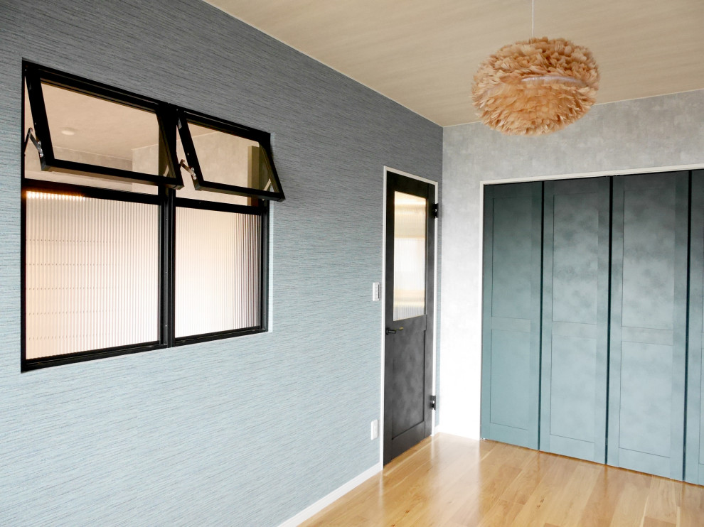 Modelo de dormitorio principal contemporáneo pequeño sin chimenea con paredes grises, suelo de contrachapado, suelo marrón, papel pintado y papel pintado