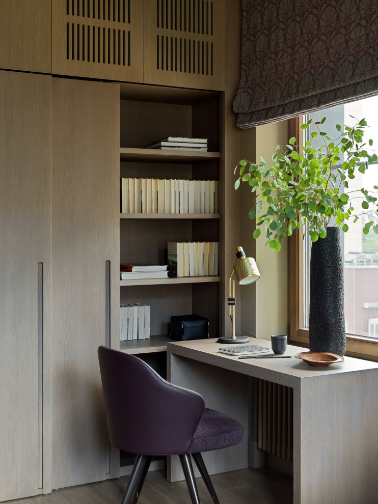This is an example of a mid-sized contemporary study room in Moscow with beige walls, medium hardwood floors, a freestanding desk and brown floor.
