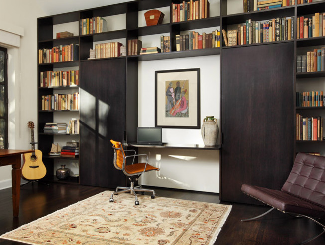 Large contemporary home office in Austin with a library, white walls, dark hardwood floors, a built-in desk, no fireplace and brown floor.