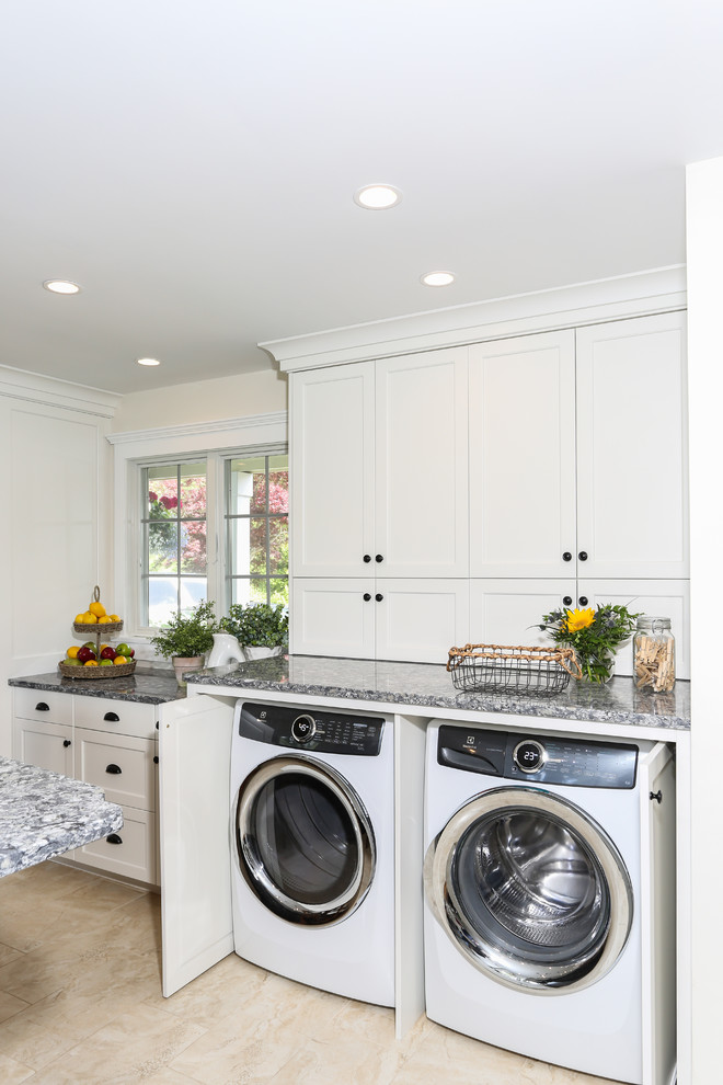 Inspiration for a large traditional u-shaped laundry room in Boston with shaker cabinets, a farmhouse sink, white cabinets, granite benchtops, grey splashback, marble splashback, ceramic floors, black floor and grey benchtop.