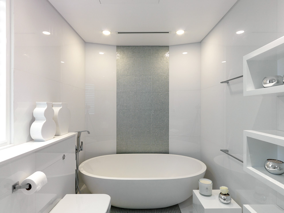 Large contemporary master bathroom in Other with a freestanding tub, white tile, stone tile, beige walls, travertine floors, white cabinets and a wall-mount toilet.