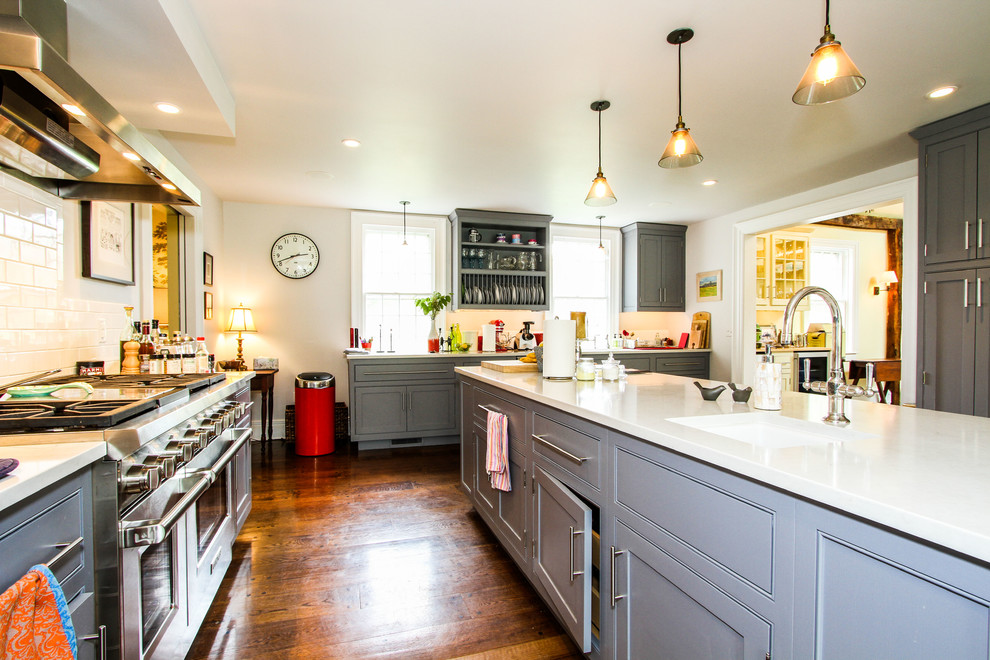Example of a large classic medium tone wood floor eat-in kitchen design with a farmhouse sink, raised-panel cabinets, stainless steel appliances and an island