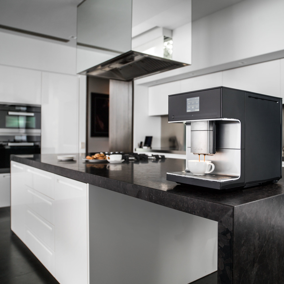 This is an example of a large contemporary galley separate kitchen in Oxfordshire with white cabinets, black appliances, dark hardwood floors and with island.